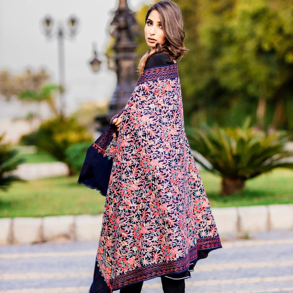 Woman outdoors wearing a Kashmiri shawl with vibrant floral embroidery and beige base