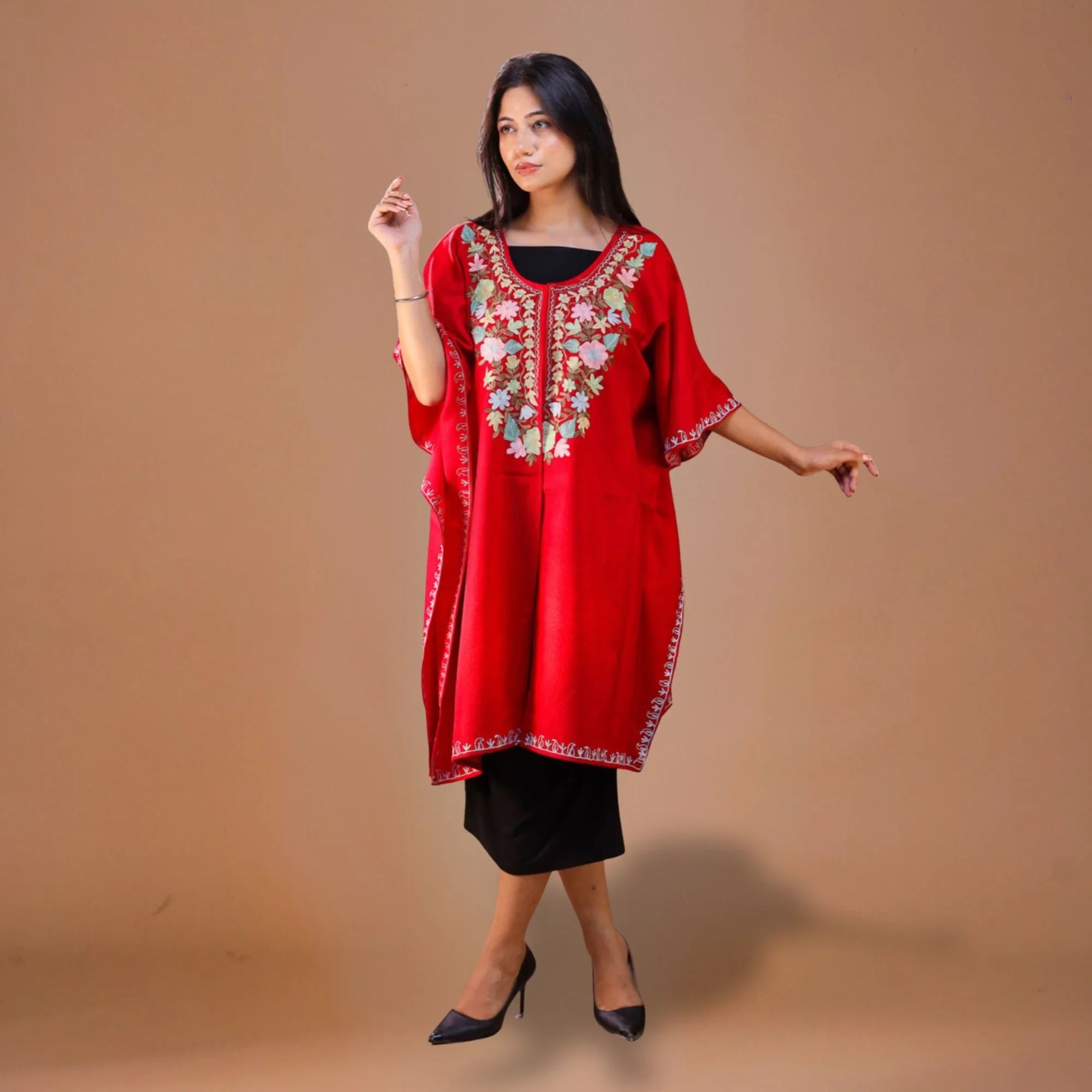 Woman in a red Kashmiri kaftan with floral embroidery, standing against a plain background
