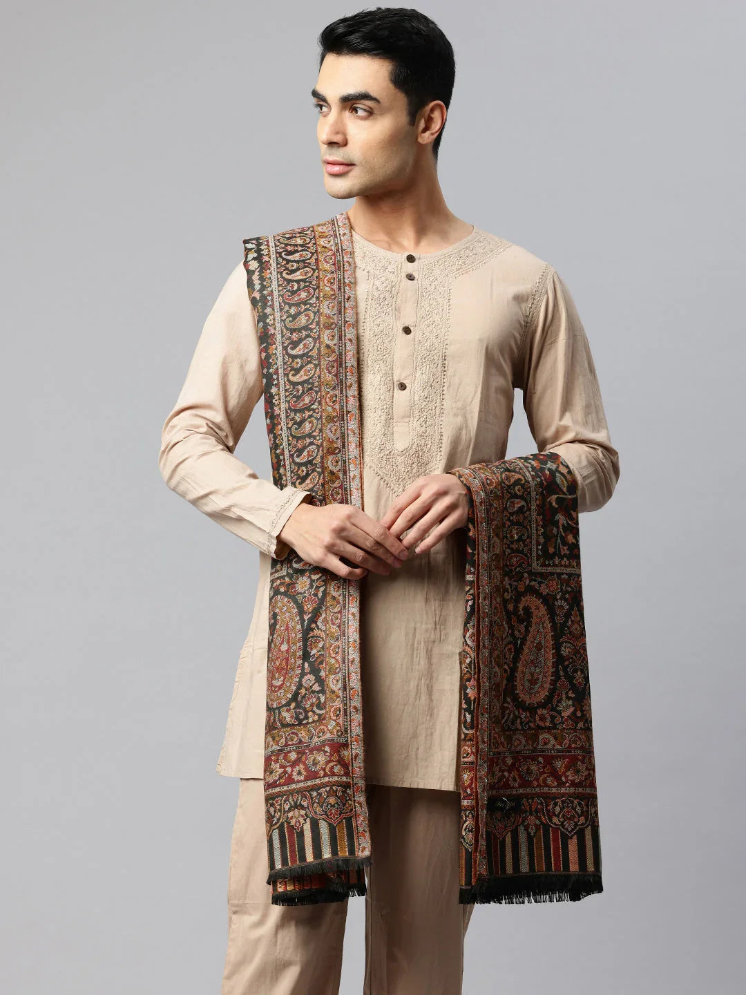 Man in beige kurta wearing a Kani shawl with intricate floral and paisley embroidery