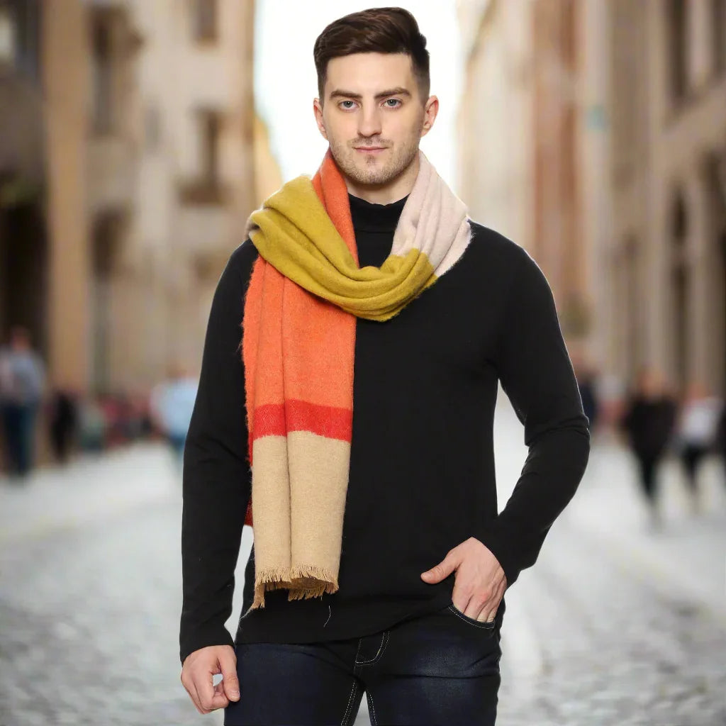 Man outdoors wearing a color-block wool scarf in mustard yellow, orange, and beige