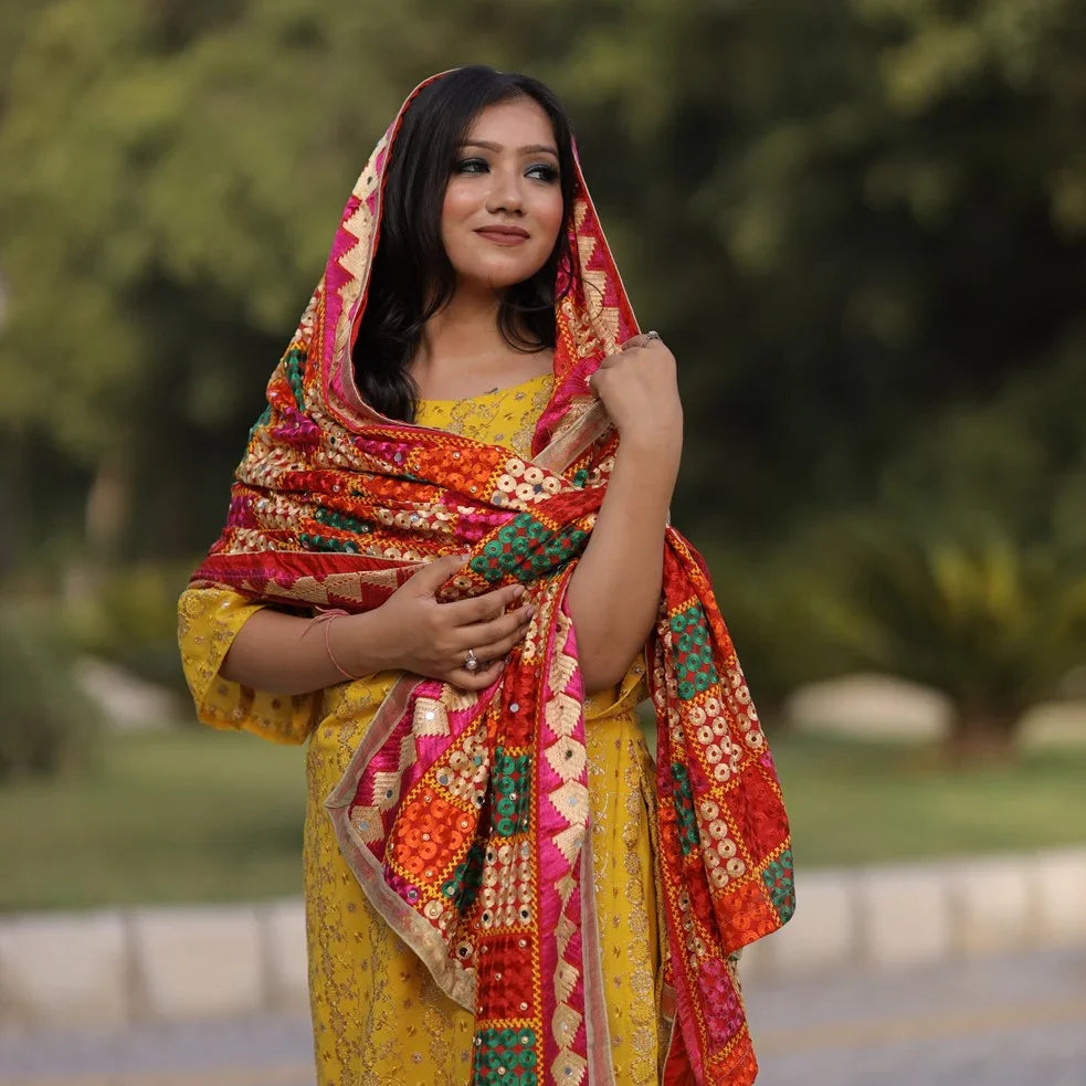 Woman outdoors wearing a Kashmiri shawl with vibrant floral embroidery and beige base