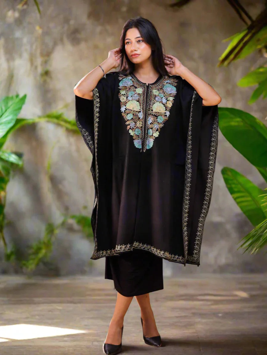 Woman in a red Kashmiri kaftan with floral embroidery, standing against a plain background